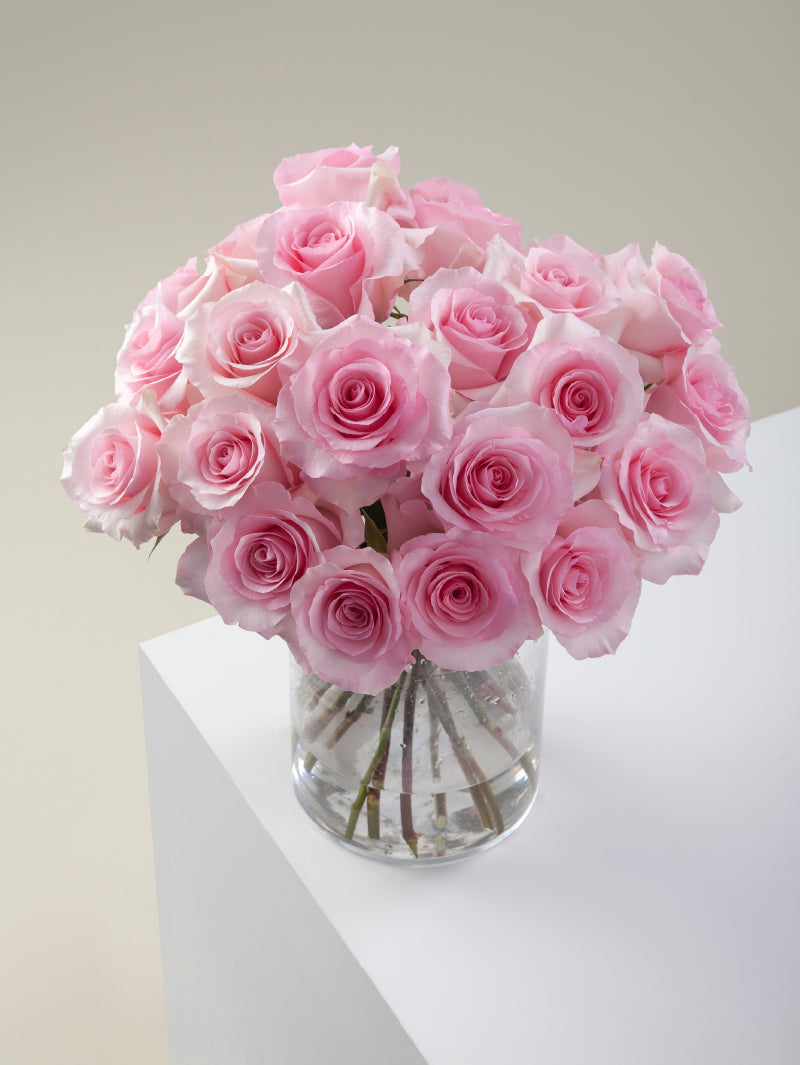 Bouquet of pink roses arranged in a glass vase on a light background.

#color_pink