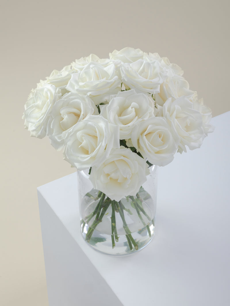 Bouquet of white roses arranged in a glass vase on a light background.

#color_white
