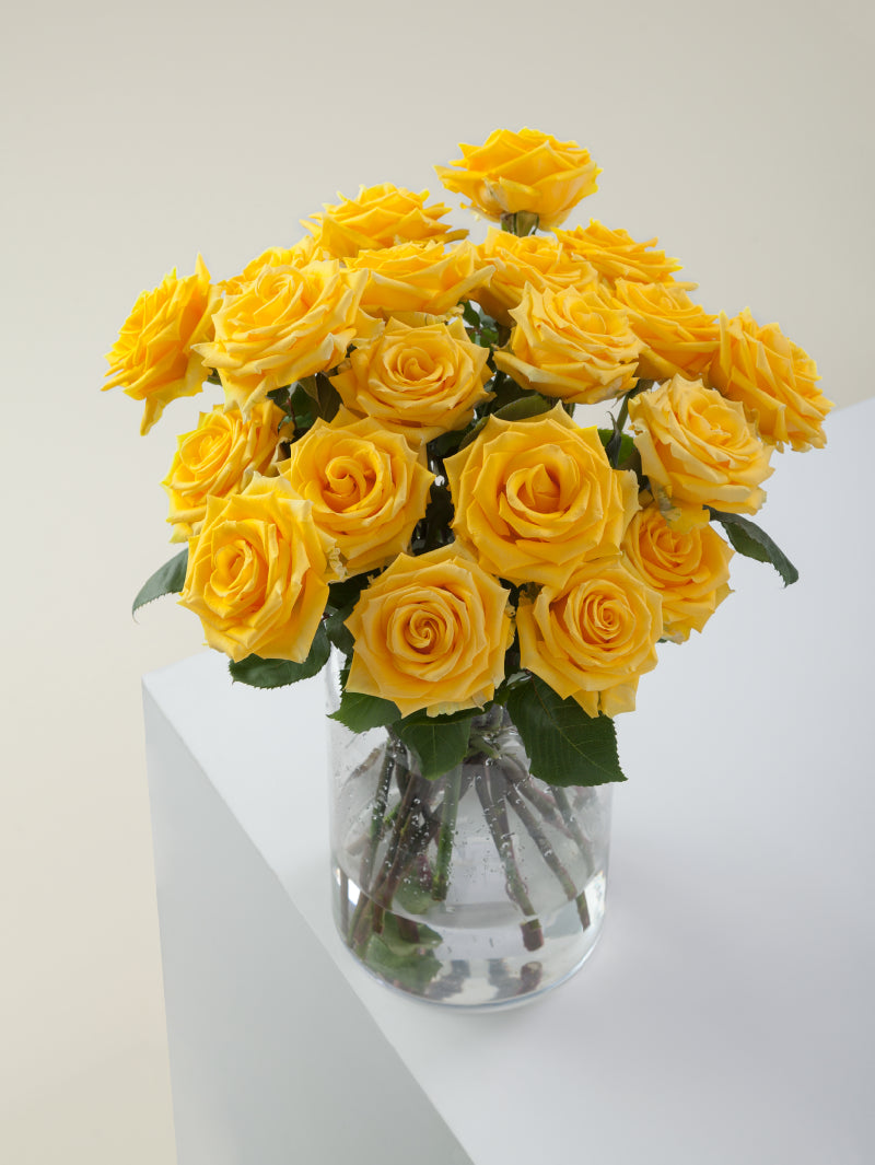 Bouquet of yellow roses arranged in a glass vase on a light background.

#color_yellow